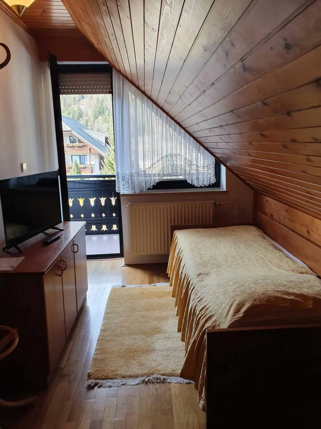 Soba pod lesenim stropom z vrati na balkon